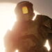 تصویر ضدنور (Silhouette) از مستر چیف (Master Chief) با زره نمادین سبز رنگ و کلاهخود طلایی که در مقابل یک منبع نور شدید و درخشان ایستاده است. نور خورشید یا یک پورتال فضایی از پشت سر او میتابد و هالهای درخشان دور شخصیت ایجاد کرده است