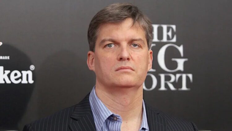 پرتره کلوزآپ از مایکل بری (Michael Burry)، سرمایه‌گذار مشهور و مدیر صندوق تامین سرمایه، با کت و شلوار راه راه و پیراهن آبی، در حال شرکت در یک رویداد تبلیغاتی فیلم The Big Short با پس‌زمینه برند Heineken
