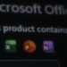 تصویر تاریک و خارج از فوکوس (Bokeh) از صفحه نمایش که عنوان نارنجی رنگ “Office” و متن کمرنگ “Microsoft Office Home and Stud” را در بخش بالایی آیکونهای برنامههای آفیس نشان میدهد.