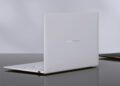 رندر استودیویی از نمای پشت لپ‌تاپ Asus Zenbook Air 2026 به رنگ سفید سرامیکی؛ لوگوی نقره‌ای ASUS Zenbook در مرکز پنل پشتی دیده می‌شود و دستگاه روی یک میز براق تیره قرار گرفته که بازتاب بدنه ظریف و مینیمال آن را نشان می‌دهد