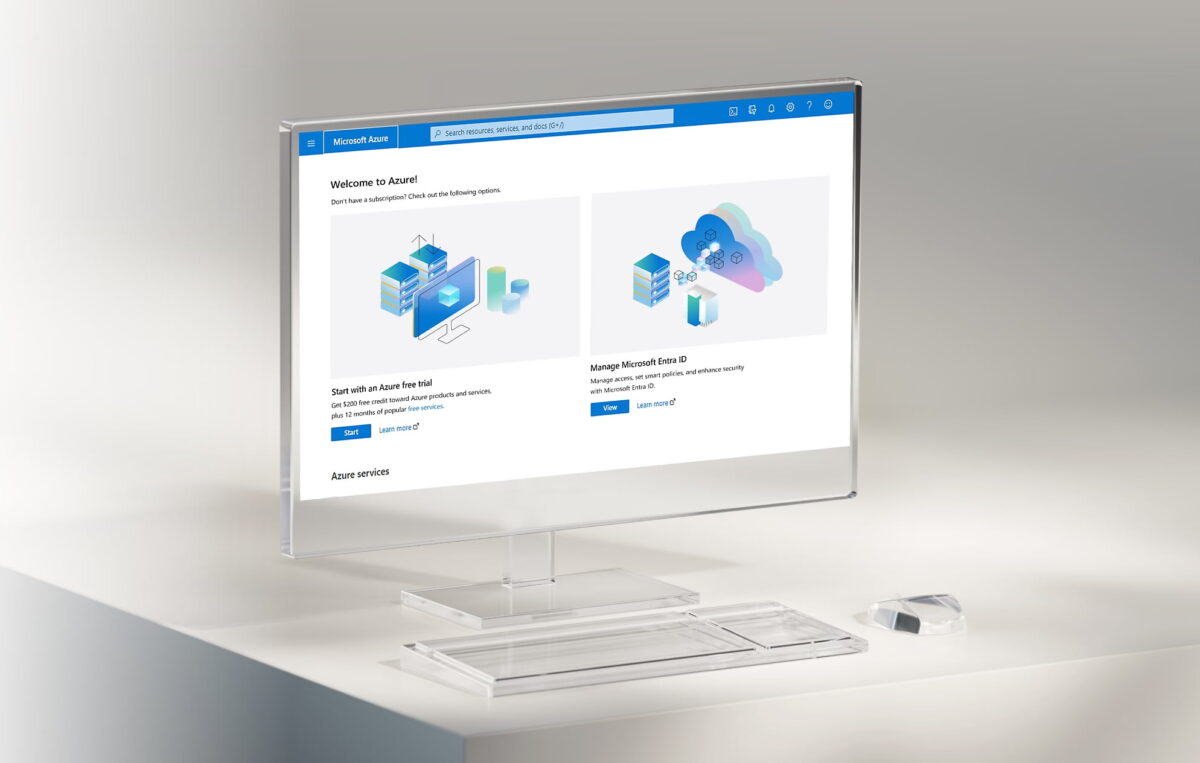 یک مانیتور شیشهای و شفاف مدرن روی میز کار که صفحهی خوشآمدگویی پورتال Microsoft Azure را با دو بنر شروع دورهی آزمایشی رایگان (Azure free trial) و مدیریت هویت (Microsoft Entra ID) به تصویر کشیده است.