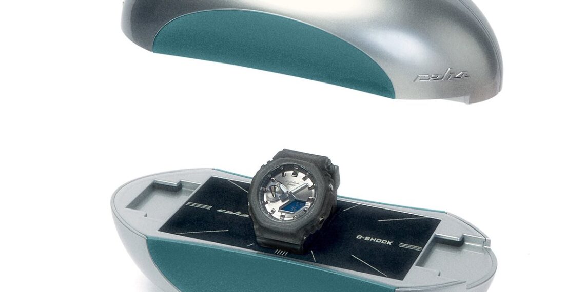 ساعت مچی Casio G-Shock مدل GA-2100 در همکاری با برند C2H4، درون جعبهای خاص و بیضویشکل به رنگ نقرهای و فیروزهای که به صورت معلق نمایش داده شده است.