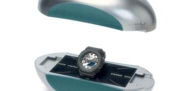 ساعت مچی Casio G-Shock مدل GA-2100 در همکاری با برند C2H4، درون جعبه‌ای خاص و بیضوی‌شکل به رنگ نقره‌ای و فیروزه‌ای که به صورت معلق نمایش داده شده است.