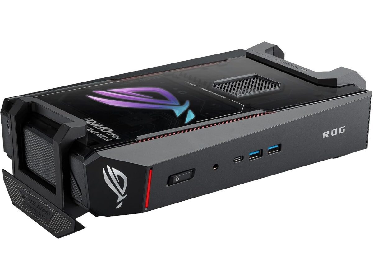 نمای زاویهدار از کیس مینی پیسی ASUS ROG NUC که به صورت افقی روی سطح قرار گرفته است. پنل شفاف بالایی با لوگوی درخشان ROG و عبارت For Those Who Dare به همراه ورودیهای ورودی/خروجی جلو و دکمه پاور مشخص است.