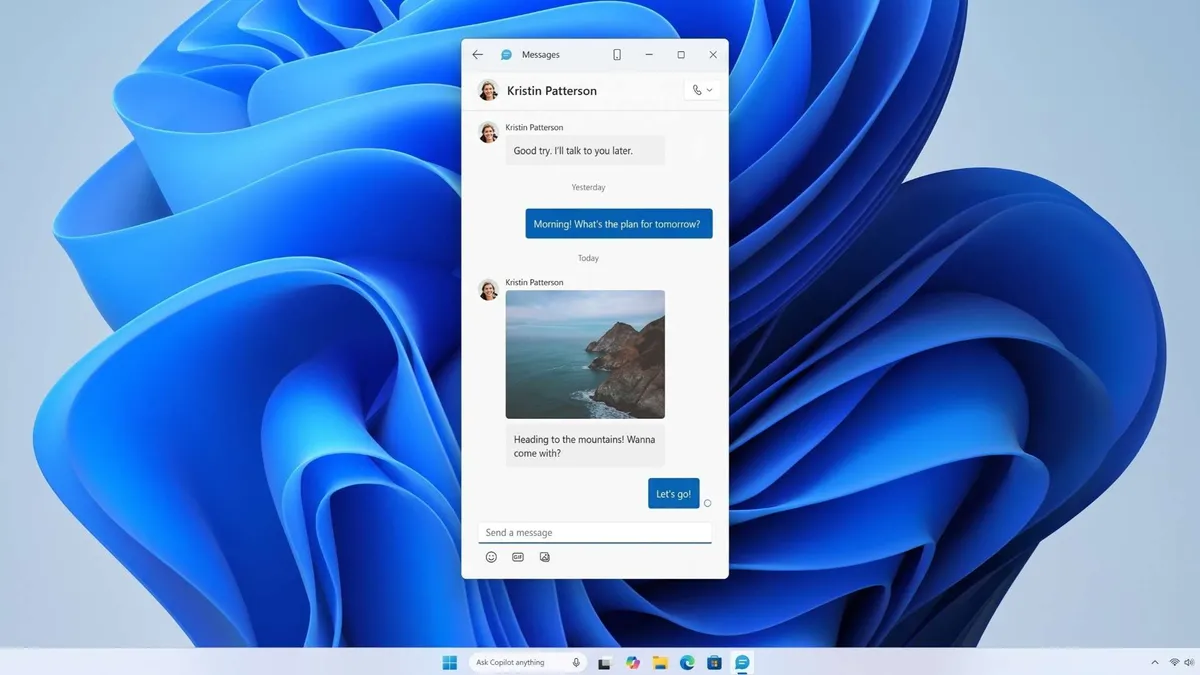 رابط کاربری اپلیکیشن Messages در ویندوز ۱۱ که بر روی پسزمینه پیشفرض آبی (Bloom) باز شده است. در پنجره چت، پیامهایی از مخاطبی به نام Kristin Patterson به همراه یک تصویر منظره ساحلی دیده میشود.