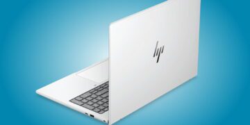 نمای پشت لپتاپ HP EliteBook نقرهای با لوگوی براق HP روی پسزمینه آبی، در حالت نیمهباز که بخشی از کیبورد و درگاههای سمت چپ آن دیده میشود