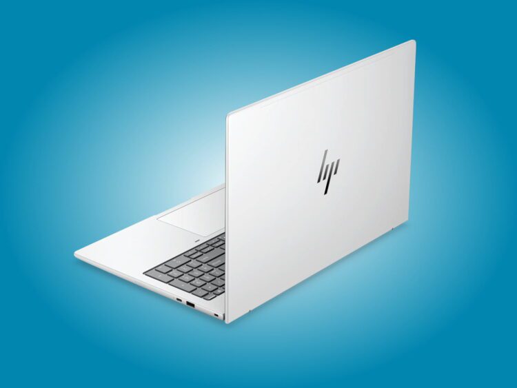 نمای پشت لپتاپ HP EliteBook نقرهای با لوگوی براق HP روی پسزمینه آبی، در حالت نیمهباز که بخشی از کیبورد و درگاههای سمت چپ آن دیده میشود