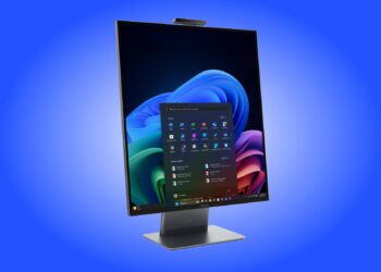 رندر تبلیغاتی کامپیوتر همه‌کاره لنوو (ThinkCentre AIO) با نمایشگر بدون حاشیه و نسبت تصویر عمودی که در محیط ویندوز ۱۱ قرار دارد؛ منوی استارت و اپلیکیشن‌های پین شده در مرکز صفحه دیده می‌شوند و یک وب‌کم عریض در لبه بالایی دستگاه تعبیه شده است. کل دستگاه روی یک پایه فلزی تخت و مدرن با لوگوی لنوو در پس‌زمینه‌ای با طیف رنگی آبی قرار گرفته است