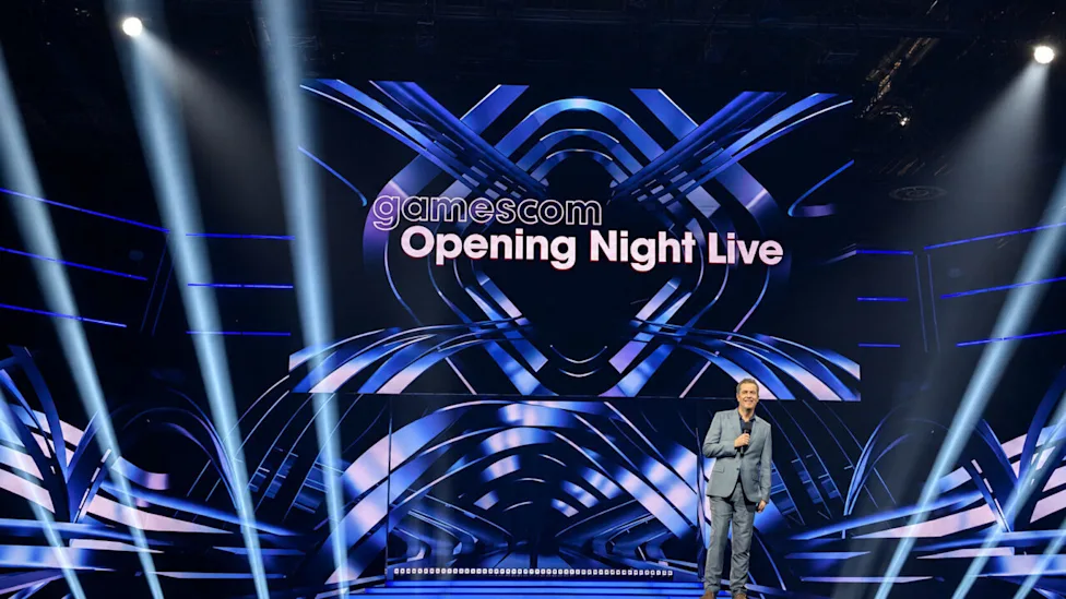 جف کیلی در حال اجرای زنده روی استیج گیمزکام مقابل نمایشگر بزرگ آبی‌رنگ با عنوان Gamescom Opening Night Live.