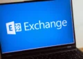 نمای نزدیک لپ‌تاپ روی میز که لوگوی Microsoft Exchange را روی پس‌زمینه آبی نمایش می‌دهد.