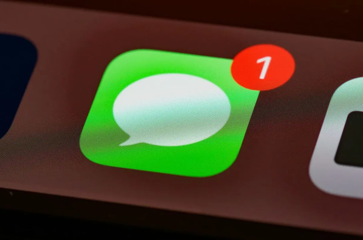 نمای نزدیک از آیکون سبز اپلیکیشن Messages اپل روی نمایشگر، همراه با نشان اعلان قرمز با عدد یک.