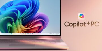 نمای نزدیک از لپتاپی با والپیپر رنگارنگ ویندوز ۱۱ و لوگوی درخشان Copilot+ PC در کنار صفحهنمایش.