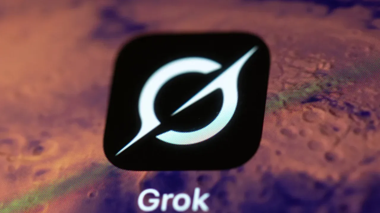 نمای نزدیک از لوگوی سفید Grok روی یک مربع مشکی، در برابر پسزمینهای تار و بنفشرنگ که بخشی از رابط کاربری یا نمایشگر را نشان میدهد.