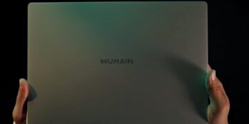 نمای پشتی لپتاپ باریک Humain با لوگوی این شرکت، در دست یک فرد و مقابل پسزمینهای تاریک.