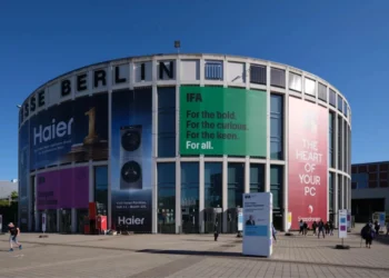 نمای بیرونی ساختمان مدور مرکز همایش‌های Messe Berlin با بنرهای تبلیغاتی بزرگ شرکت‌های هایر، اسنپدراگون و لوگوی نمایشگاه IFA در روز آفتابی.