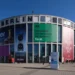 نمای بیرونی ساختمان مدور مرکز همایشهای Messe Berlin با بنرهای تبلیغاتی بزرگ شرکتهای هایر، اسنپدراگون و لوگوی نمایشگاه IFA در روز آفتابی.