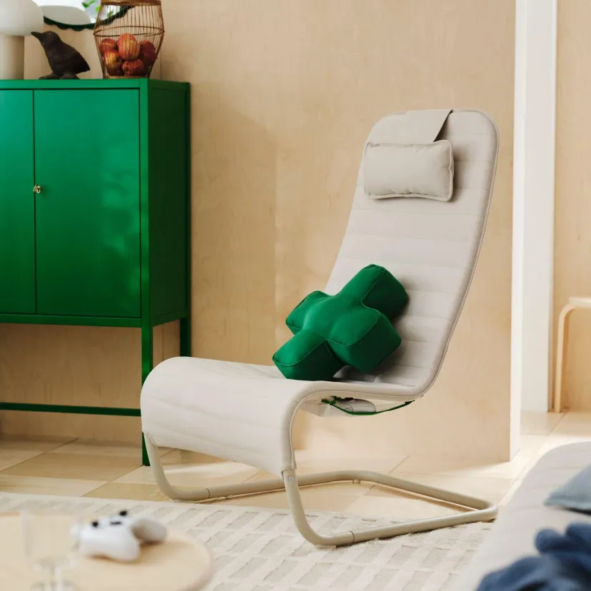 چیدمان اتاق نشیمن با محصولات مجموعه IKEA و Xbox شامل نمایشگر روی پایه چرخدار، صندلی سفید، چهارپایه سبز، کنسول بازی و دستههای بازی.