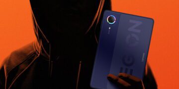 یک پرتره تاریک و سایهروشن از فردی هودیپوش با عینک که تبلت گیمینگ لنوو Legion را با بدنه پشتی سرمهایرنگ، ماژول دوربین دایرهای با حلقه نوری رنگینکمانی و نوشته بزرگ LEGION در دست دارد. پسزمینه تصویر نارنجی یکدست است.