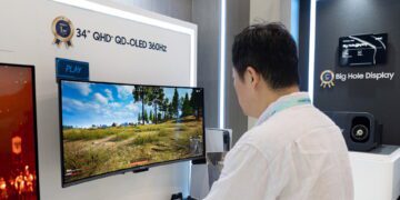 بازدیدکنندهای در حال تماشای مانیتور فوق عریض ۳۴ اینچی QHD پلاس QD-OLED با نرخ نوسازی ۳۶۰ هرتز و نمایش یک بازی ویدیویی در نمایشگاه.