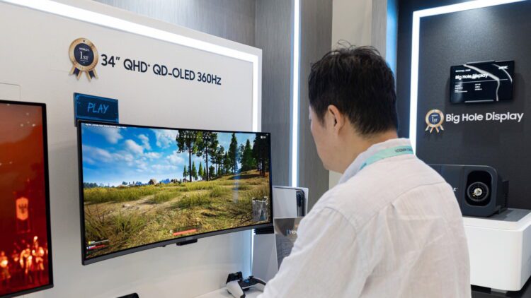 بازدیدکنندهای در حال تماشای مانیتور فوق عریض ۳۴ اینچی QHD پلاس QD-OLED با نرخ نوسازی ۳۶۰ هرتز و نمایش یک بازی ویدیویی در نمایشگاه.