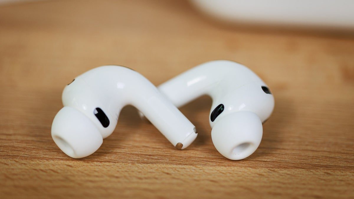 یک جفت AirPods Pro سفید اپل با سریهای سیلیکونی روی سطح چوبی