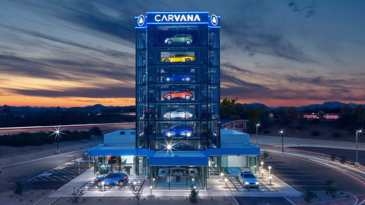 برج شیشهای چندطبقه Carvana با خودروهای رنگارنگ در طبقات مختلف که بهعنوان دستگاه فروش خودروی خودکار در زمان غروب آفتاب دیده میشود.
