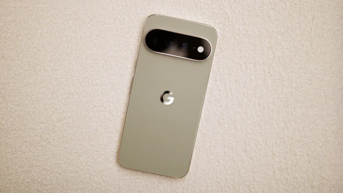 پشت یک گوشی Google Pixel به رنگ سبز-طلایی روشن روی پسزمینهای کرمرنگ، با نوار افقی مشکی دوربین و لوگوی G در مرکز بدنه.
