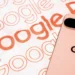 نمای پشت گوشی صورتی Google Pixel روی پس‌زمینه‌ای با نوشته‌های Google Pixel