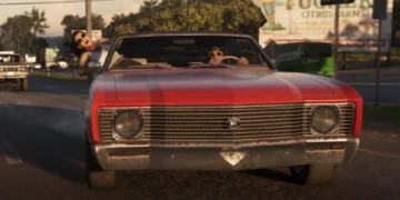 صحنهای از بازی GTA 6 با حضور لوسیا آویزان از پنجره و جیسون پشت فرمان یک ماشین کلاسیک قرمز در حال حرکت در جاده.