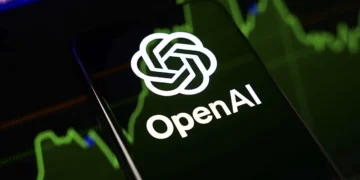 لوگوی شرکت OpenAI روی تلفن همراه در کنار نمودارهای مالی