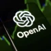 لوگوی شرکت OpenAI روی تلفن همراه در کنار نمودارهای مالی