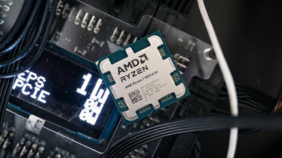 پردازنده AMD Ryzen 7 9850X3D روی مادربرد و در میان کابلها و قطعات داخلی کامپیوتر، با نمایشگر روشن سیستم در پسزمینه.