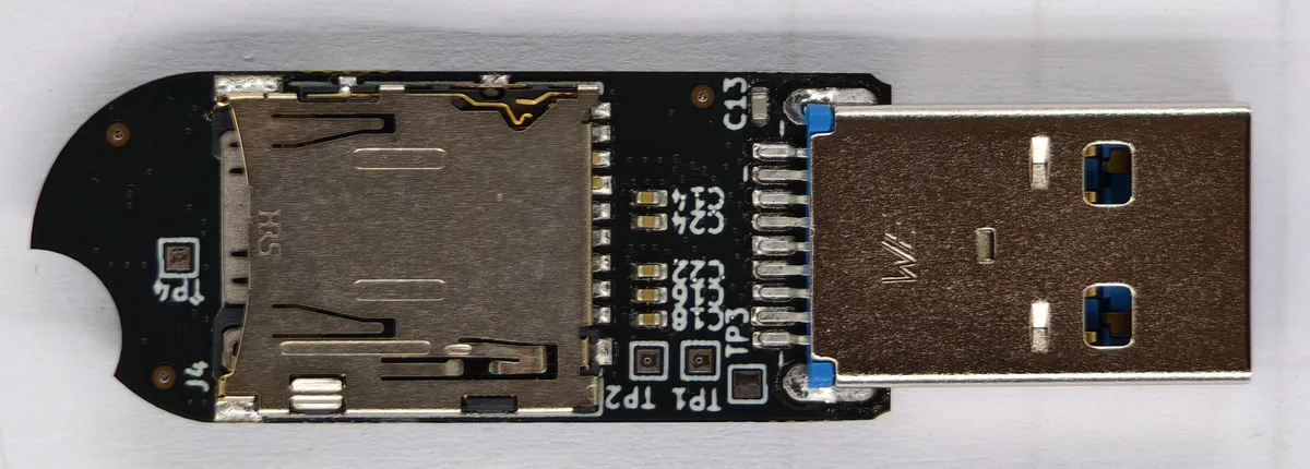 نمای داخلی یک فلشمموری دارای شیار کارت microSD، کانکتور USB-A و برد مدار چاپی مشکی با چند قطعه الکترونیکی و خازنهای سطحی