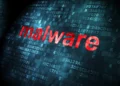 طرح مفهومی امنیت سایبری و بدافزار با کلمه قرمز رنگ و درخشان malware روی پسزمینهای از کدهای دیجیتال هگزادسیمال، بیتهای داده و ماتریس باینری آبی تیره.