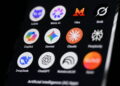 آیکون برنامههای مختلف هوش مصنوعی شامل DeepSeek، ChatGPT، Gemini، Claude، Copilot و Grok روی صفحه نمایش گوشی با پسزمینه مشکی