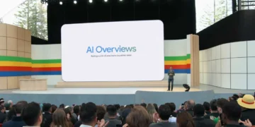 سوندار پیچای روی استیج رویداد گوگل در برابر حضار در حال معرفی بخش جستوجوی هوشمند AI Overviews روی صفحه نمایش بزرگ سالن