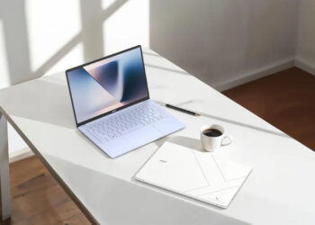 لپتاپ بازشده ایسر سوییفت بلید ۱۴ در کنار لپتاپ بسته و فنجان قهوه روی میز کار سفید مدرن و روشن با تابش نور آفتاب.