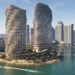 نمای سینمایی برجهای مسکونی دو قلوی موجدار شیشهای Vice City در پسزمینه آسمان آبی صاف، با برجهای مسکونی شهر در پسزمینه، درختان نخل روی برآمدگیهای جزیره و قایقهای متحرک در آبهای فیروزهای روشن؛ پلهای طولانی در افق دوردست دیده میشوند و یک بالگرد در پرواز است.