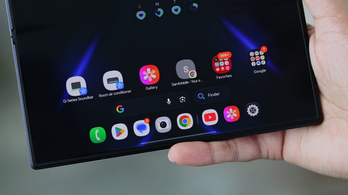نمای نزدیک از دستی که تبلت تاشده Samsung Galaxy Z Fold 8 را باز نگرفته؛ صفحه نمایش بزرگ با ویجتها و اپلیکیشنهای خانه هوشمند مانند کولر گازی و ساندبار Q-Series، در تم تیره با پیکانهای آبی.