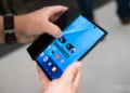 نمای دستهای دو نفر از بالا روی گوشی تاشو سهبعدی سامسونگ Galaxy Z TriFold روشن
