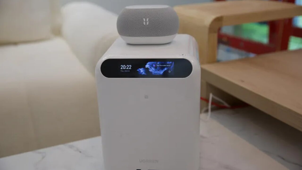 دستگاه ذخیرهساز سفید رنگ UGREEN به همراه نمایشگر کوچک جلویی و ساعت دیجیتال با بلندگوی هوشمند قرار گرفته روی آن در دکوراسیون اتاق.