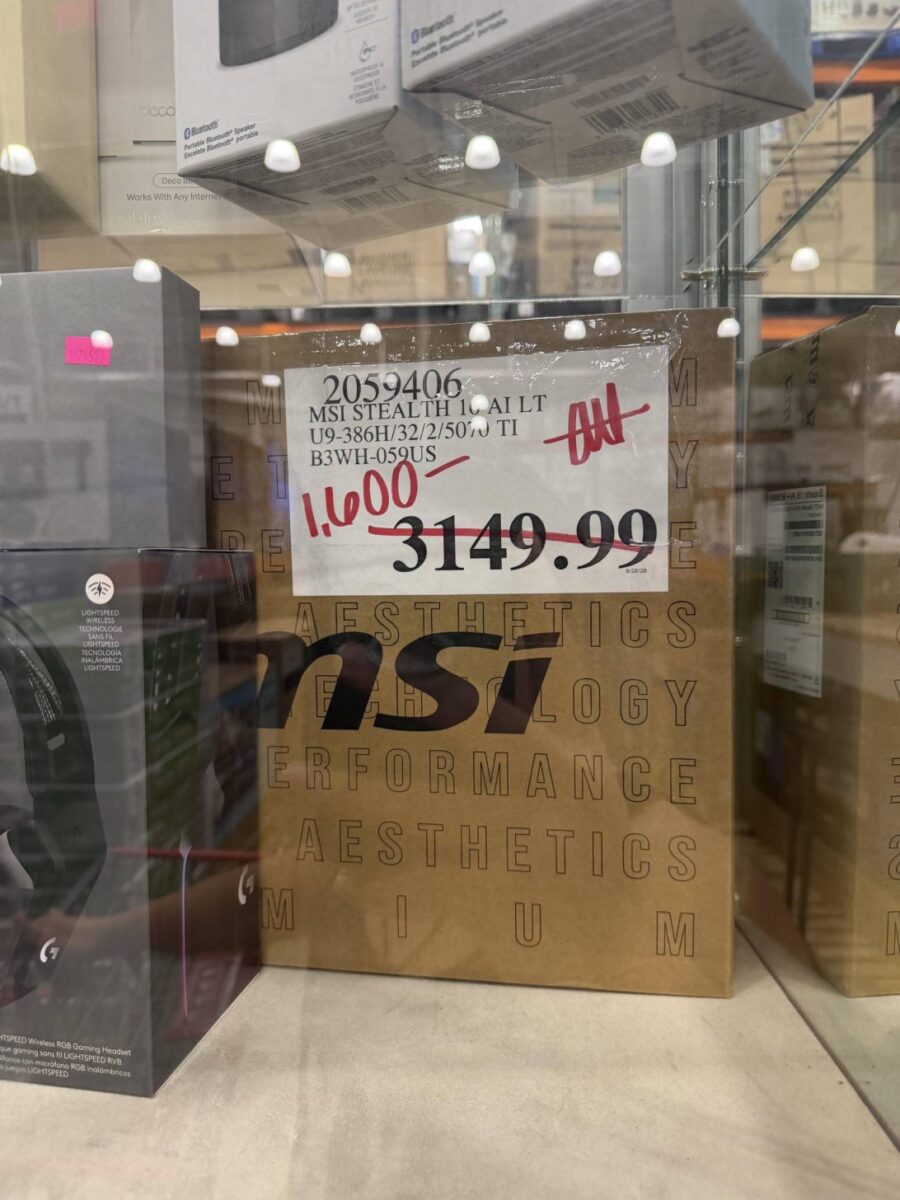 جعبهی قهوهای لپتاپ MSI Stealth 16 AI در ویترین فروشگاه با برچسب قیمت ۱٬۶۰۰ دلار که قیمت قبلی ۳٬۱۴۹.۹۹ دلار روی آن خط خورده، کنار جعبهی هدفون گیمینگ Logitech.
