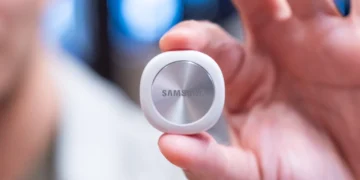 ردیاب هوشمند سفید سامسونگ با بخش میانی فلزی چرخان و لوگوی Samsung که بین انگشتان دست نگه داشته شده است.