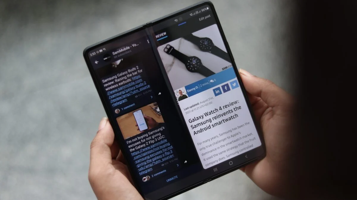 نمای نزدیک از گوشی تاشو Samsung Galaxy Z Fold 3 که در حالت باز شده و در دست گرفته شده و صفحهنمایش بزرگ آن دو بخش جداگانه از یک وبسایت خبری را به صورت Split Screen نمایش میدهد.