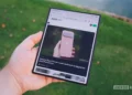 نمای دستی که تبلت تاشده Samsung Galaxy Z Fold 8 Ultra را در حالت باز نگرفته؛ صفحه نمایش نمایش وبسایت اندروید اتوریتی در ماده‌ی ۲۵.۳ با مقاله Pixel 11 Pro در حاشیه سبز محو و بعد از پس‌زمینه.