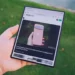 نمای دستی که تبلت تاشده Samsung Galaxy Z Fold 8 Ultra را در حالت باز نگرفته؛ صفحه نمایش نمایش وبسایت اندروید اتوریتی در مادهی ۲۵.۳ با مقاله Pixel 11 Pro در حاشیه سبز محو و بعد از پسزمینه.