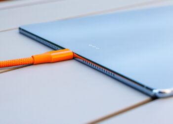 نمای جانبی تبلت هواوی MatePad Pro Max در حالت شارژ با کابل بافت‌دار نارنجی متصل به پورت USB-C، همراه با دکمه‌های کناری و بلندگوهای سوراخ‌دار روی لبه بدنه.