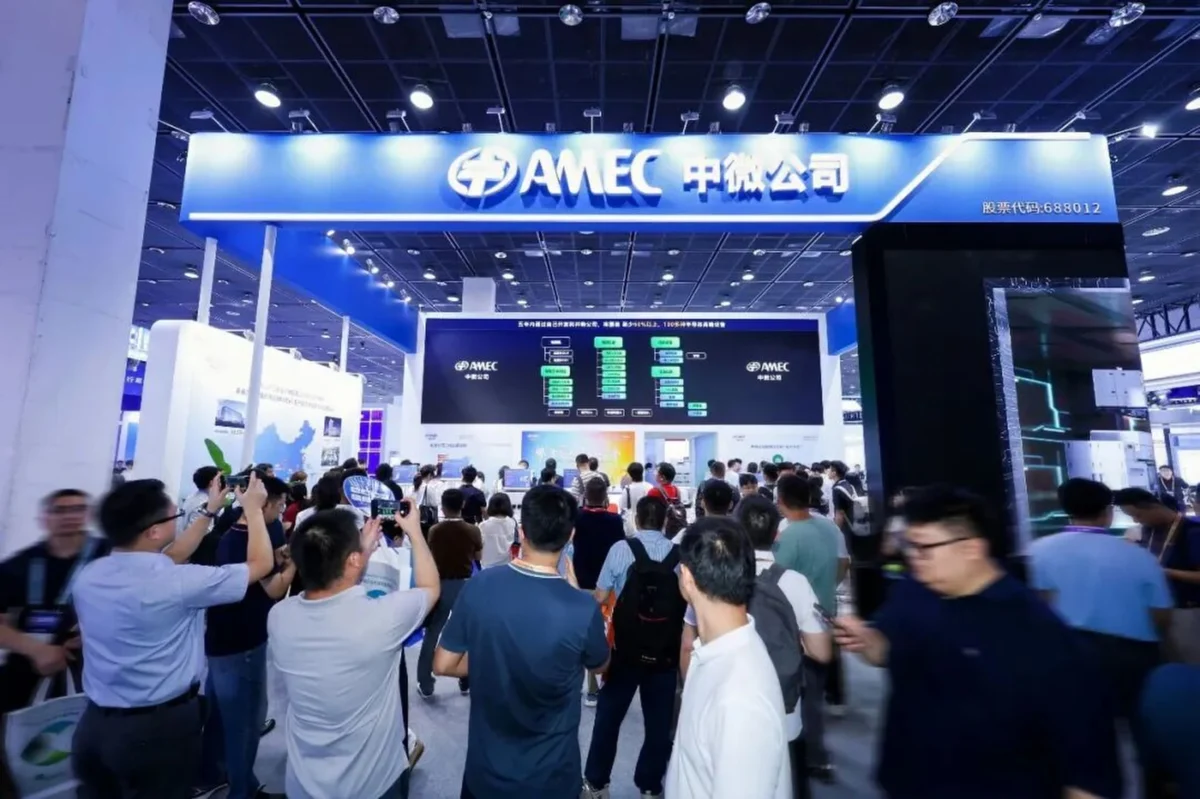 غرفه شرکت نیمههادی AMEC در یک نمایشگاه بینالمللی با تابلو نوری آبیرنگ، صفحه نمایش بزرگ ارائه محصولات و جمعیتی از بازدیدکنندگان و متخصصان در حال عکاسی و بازدید.