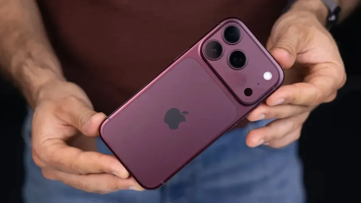 یک iPhone 18 Pro به رنگ بنفش تیره در دست گرفته شده و نمای پشت دستگاه با سه لنز دوربین، لوگوی Apple و فلاش دوربین را نشان میدهد.