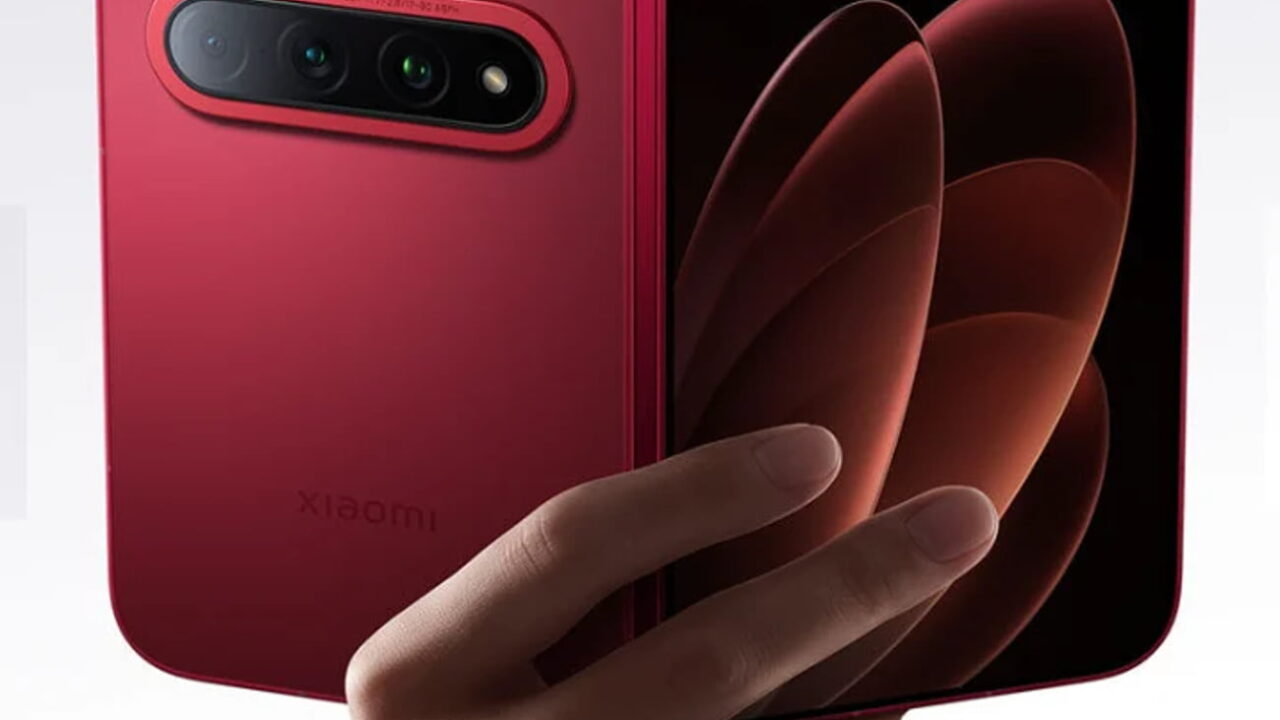 دست کاربر گوشی تاشو قرمز Xiaomi 18 Fold را در حالت نیمهباز نگه داشته؛ از پشت ماژول دوربین سهگانه و لوگوی Xiaomi و از رو، نمایشگر داخلی با والپیپر انتزاعی نارنجی دیده میشود.
